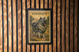 A framed illustration of a dog, specifically a Keeshond, is displayed on a wooden wall.