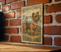 a framed illustration of a dog, specifically a Norfolk Terrier, mounted on a brick wall.