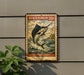 A vintage-style metal sign featuring a black marlin fish, mounted on a wall next to a plant.
