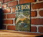 A vintage-style sign for the Ace Basin National Wildlife Refuge in South Carolina, featuring a white egret and a crocodile in a tropical landscape.
