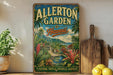 A vintage-style metal sign for Allerton Garden in Hawaii, featuring a tropical landscape with palm trees, flowers, and a path leading to a waterfall.