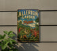 A vintage metal sign for Allerton Garden in Hawaii, featuring a tropical landscape with palm trees, flowers, and a mountain backdrop.