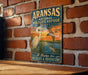 A vintage-style metal sign for the Arkansas National Wildlife Refuge in Texas, featuring illustrations of wildlife and a sunset.