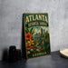 A vintage-style metal sign for the Atlanta Botanical Garden in Georgia, featuring a colorful illustration of the garden and the city skyline.