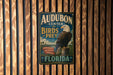 A vintage-style metal sign for Audubon Center for Birds of Prey in Florida, featuring an image of an eagle.