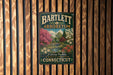 A vintage-style metal sign for Bartlett Arboretum in Connecticut, featuring a scenic landscape with trees, flowers, and a bridge.