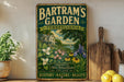 A vintage-style metal sign for "Bartram's Garden" in Pennsylvania, featuring a lush garden scene with flowers and a house.