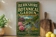 A vintage-style metal sign for the Berkshire Botanical Garden, featuring a garden scene with a gazebo, flowers, and a pond.