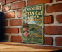 A vintage-style metal sign for the Berkshire Botanical Garden, featuring a garden scene with pink flowers and a bridge in the background.