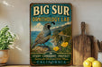A vintage-style metal sign for the Big Sur Ornithology Lab, featuring a quail bird and a scenic landscape with a bridge and mountains.