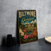 A vintage-style metal sign for the Baltimore Estate Gardens in North Carolina, featuring a castle and flowers, is displayed on a gray countertop.