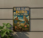 A vintage-style metal sign for the Block Island Bird Sanctuary, featuring an illustration of an owl and a lighthouse, is displayed on a wall.