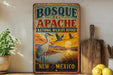 A vintage-style metal sign for Bosque del Apache National Wildlife Refuge in New Mexico, featuring a scenic landscape with a crane and birds in flight.