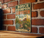 A vintage-style metal sign for the Boyce Thompson Arboretum in Arizona, featuring a desert landscape with cacti and other desert plants.