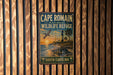 A vintage-style metal sign for Cape Romain National Wildlife Refuge in South Carolina, featuring a bird flying over a beach scene with palm trees and a lighthouse.