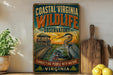 a vintage-style metal sign for the Coastal Virginia Wildlife Observation, with a bird illustration and a wooden cutting board in the background.