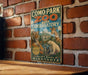 a vintage-style sign for Como Park Zoo and Conservatory, with illustrations of various animals such as a tiger, giraffe, and polar bear. The sign is displayed on a brick wall, and there is a wooden table below it.