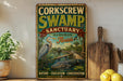 A vintage-style sign for the Corkcrew Swamp Sanctuary in Audubon, Florida, featuring an illustration of a bird and a swamp environment.