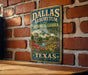 A vintage-style metal sign for the Dallas Arboretum and Botanical Garden in Texas, featuring a scenic landscape with a pond, trees, and colorful flowers.