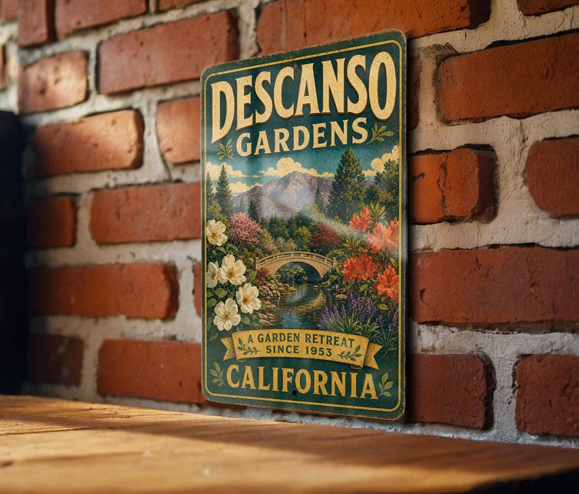 A vintage-style metal sign for Descanos Gardens, featuring a scenic landscape with mountains, flowers, and a bridge, is displayed on a brick wall.