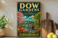 a vintage-style sign for "Dow Gardens" in Michigan, with a colorful illustration of a garden and a bridge. The sign is displayed on a shelf next to a wooden cutting board and some potted plants.