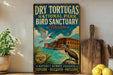 A vintage-style sign for Dry Tortugas National Park Bird Sanctuary in Florida, featuring a bird and a building in the background.