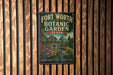A vintage-style metal sign for Fort Worth Botanic Garden in Texas, featuring a colorful illustration of a garden landscape with a waterfall and various plants.