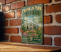 A vintage-style metal sign for Franklin Park Conservatory in Columbus, Ohio, featuring a detailed illustration of the conservatory surrounded by tropical plants and flowers.