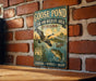 A vintage-style metal sign with a bird illustration and text, mounted on a brick wall.