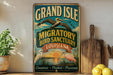 A vintage-style metal sign for the Grand Isle Migratory Bird Sanctuary in Louisiana, featuring illustrations of birds and a sunset.