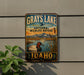 A vintage-style metal sign for the National Wildlife Refuge in Idaho, featuring a duck swimming in a lake and mountains in the background.