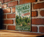 A vintage-style metal sign with the text "Green Animals Topiary Garden" is displayed on a brick wall, featuring a variety of green-covered animals such as a giraffe, dog, and turtle.
