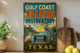 A vintage-style sign for the Gulf Coast Bird Observatory in Texas, featuring illustrations of birds and a tropical landscape.