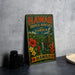 A vintage-style metal sign with the text "HAWAII TROPICAL BIOSERVE AND GARDEN" and a tropical landscape, including a waterfall and a tiki statue, is displayed on a gray countertop.