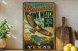 A vintage-style poster advertising the "Hawking Capital of Texas" with a hawk in flight, surrounded by a desert landscape and cacti.
