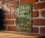 A vintage-style metal sign for the Houston Botanic Garden in Texas, featuring a lush garden scene with various plants and flowers.