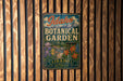 A vintage-style metal sign for the Idaho Botanical Garden, featuring a colorful illustration of flowers and plants.