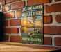 A vintage-style metal sign for the J. Clark Salyer National Wildlife Refuge, featuring a duck and a sunset, mounted on a brick wall.