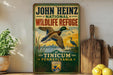 A vintage-style sign for John Heinz National Wildlife Refuge at Tinicum, Pennsylvania, featuring a duck in flight and a city skyline in the background.