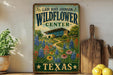 A vintage-style metal sign for the Lady Bird Johnson Wildflower Center in Texas, featuring a colorful illustration of a garden with flowers and a building in the background.