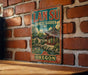 A vintage-style metal sign for the Lan Su Chinese Garden in Oregon, featuring a traditional Chinese temple and garden scene.