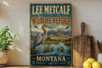 A vintage-style metal sign for Lee Metcalf National Wildlife Refuge in Montana, featuring an illustration of a heron and mountains in the background.