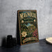 A vintage-style metal sign for Magnolia Plantation and Gardens in South Carolina, featuring a lush garden scene with a large magnolia flower.