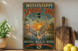 A vintage-style metal sign for the Mississippi Sandhill Crane National Wildlife Refuge, featuring illustrations of the crane and a sunset landscape.