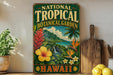 A vintage-style sign for the National Tropical Botanical Garden in Hawaii, featuring tropical flowers, plants, and a tropical landscape.
