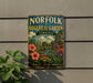 A vintage-style metal sign for the Norfolk Botanical Garden in Virginia, featuring a colorful illustration of a garden with flowers and a greenhouse.