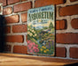 A vintage metal sign with the text "NORTH CAROLINA ARBORETUM" and a scenic illustration of a garden with a waterfall and flowers, mounted on a brick wall.