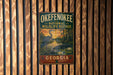 A vintage-style metal sign for the Okefenokee National Wildlife Refuge in Georgia, featuring a large blue heron and a sunset landscape.