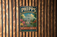 A vintage-style metal sign for the Phipps Conservatory in Pennsylvania, featuring a tropical garden scene with palm trees, flowers, and a greenhouse.