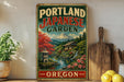 A vintage-style sign for the Portland Japanese Garden in Oregon, featuring a scenic landscape with a mountain, pagoda, and waterfall.